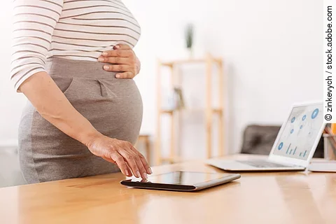 Eine schwangere Frau bedient ein Tablet.