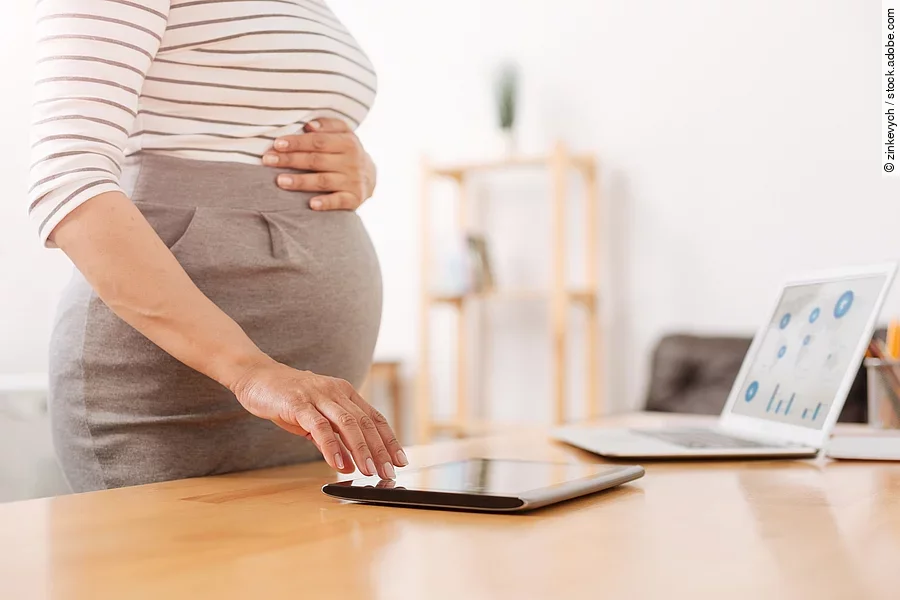 Eine schwangere Frau bedient ein Tablet.