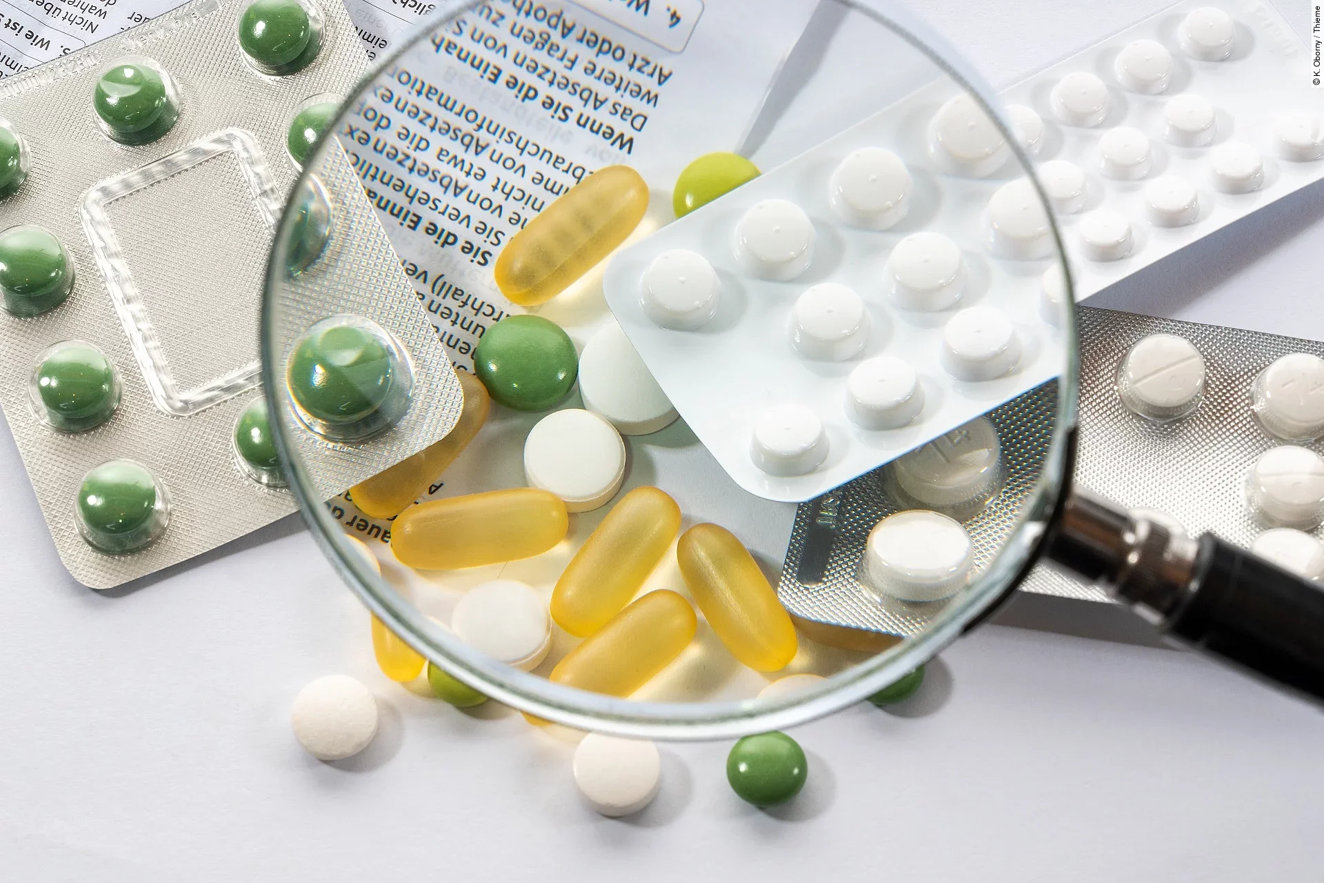 Eine Lupe wird über verschiedene Tabletten gehalten.