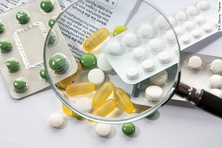 Eine Lupe wird über verschiedene Tabletten gehalten.