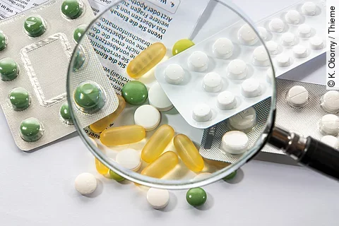 Eine Lupe wird über verschiedene Tabletten gehalten.