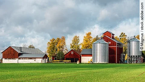 Ein Bauernhof in klassichem Schwedenrot hat eine große grünen Wiese und neu aussehende Silos. Ein Bauernhof in klassichem Schwedenrot hat eine große grünen Wiese und neu aussehende Silos.