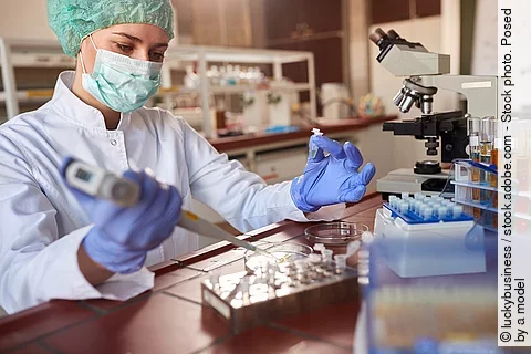 Eine Person arbeitet in einem Labor mit einer Pipette. 