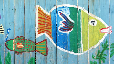 Kindermalerei mit Fischen an Lattenzaun