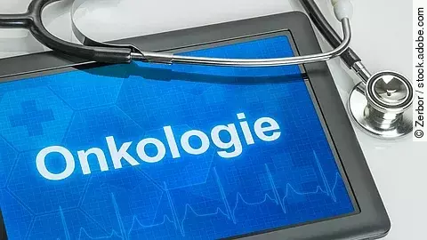 Ein schwarzes Tablet und ein schwarzes Stethoskop liegen auf einem grauen Tisch. Auf dem Tablet sieht man auf blauem Hintergrund den Schriftzug Onkologie und eine EKG-Linie.