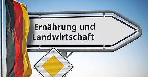Ein weißes Straßenschild weist den Weg zum Bundesministerium für Ernährung und Landwirtschaft. Daneben hängt eine Deutschlandflagge.