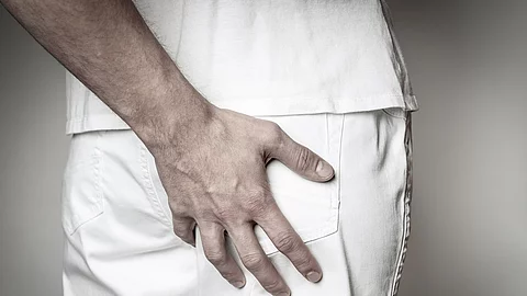 Eine Hand fasst an das Gesäß von einer anderen Person.