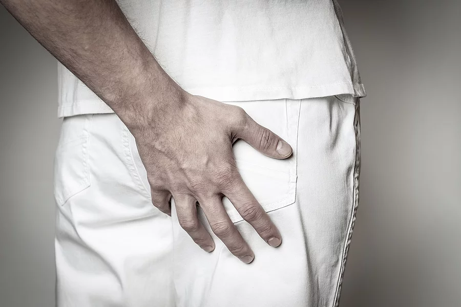 Eine Hand fasst an das Gesäß von einer anderen Person.