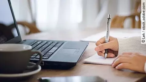 Nahaufnahme von einer am Schreibtisch arbeitenden Person.