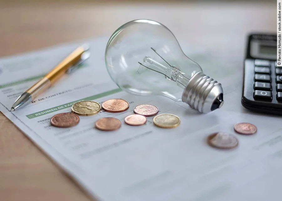 Electricity bill with light bulb, several coins, calculator and