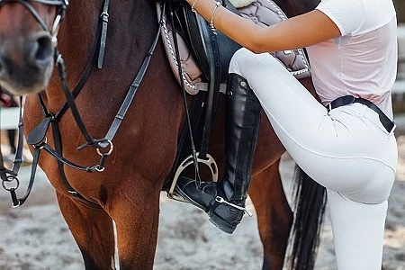 Girl rider ready for climbs, woman legs in boots with horse in t