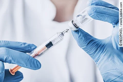 Eine medizinische Person zieht eine Spritze auf.