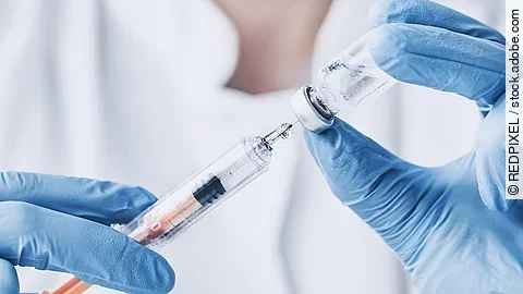 Eine medizinische Person zieht eine Spritze auf.