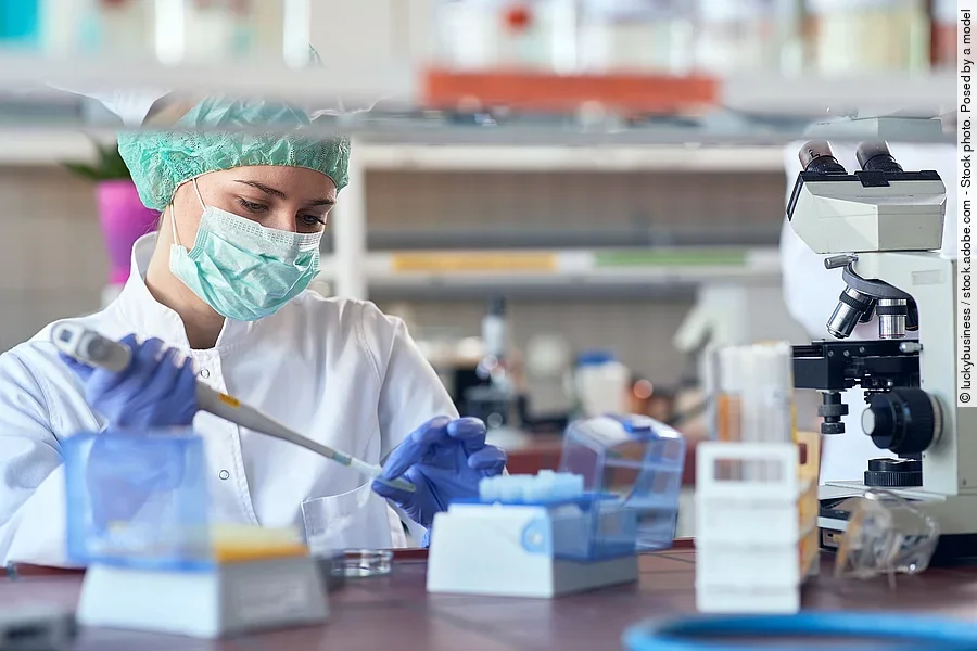 Eine Person sitzt in einem Labor und pipettiert. 