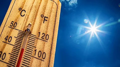 Nahaufnahme von einem Thermometer, das 40 Grad Celsius anzeigt. Im Hintergrund ist ein strahlen blauer Himmel mit nur sehr kleinen und wenig Wolken. Die Sonne strahlt stark. 