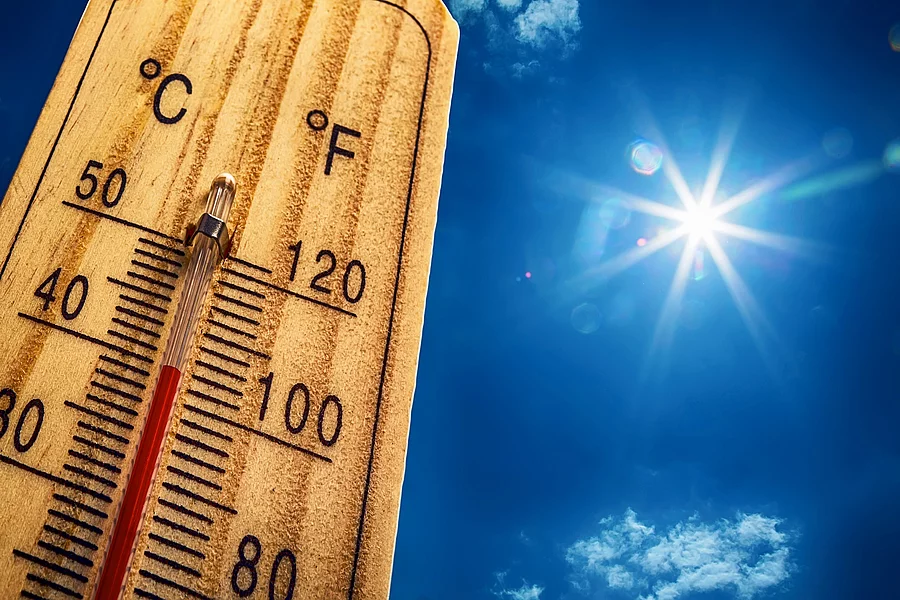 Nahaufnahme von einem Thermometer, das 40 Grad Celsius anzeigt. Im Hintergrund ist ein strahlen blauer Himmel mit nur sehr kleinen und wenig Wolken. Die Sonne strahlt stark.
