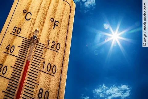 Nahaufnahme von einem Thermometer, das 40 Grad Celsius anzeigt. Im Hintergrund ist ein strahlen blauer Himmel mit nur sehr kleinen und wenig Wolken. Die Sonne strahlt stark.