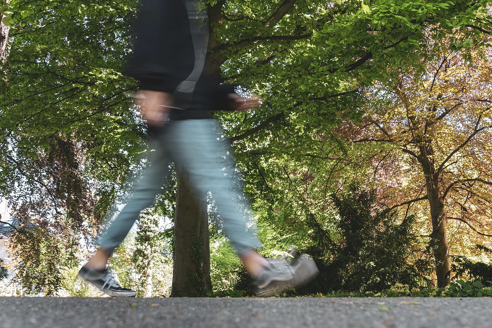 Eine durch die Fotografie verschwommene Person geht durch einen Park spazieren.