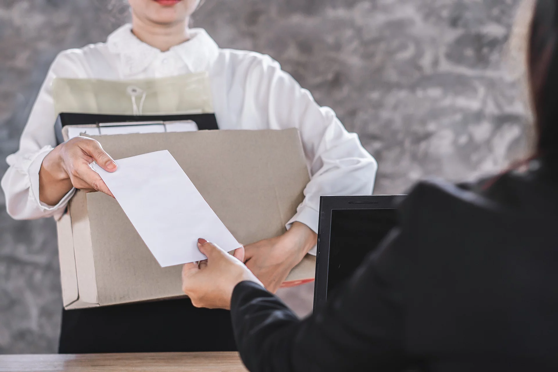 female worker hand giving resignation latter to boss quitting a job 