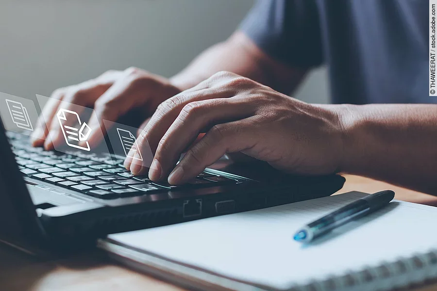 Nahaufnahme von einem Laptop an dem eine Person auf der Tastatur tippt.