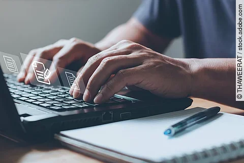 Nahaufnahme von einem Laptop an dem eine Person auf der Tastatur tippt.