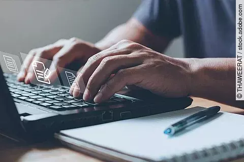 Nahaufnahme von einem Laptop an dem eine Person auf der Tastatur tippt.