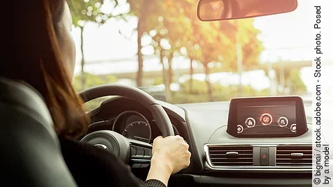 Woman driving her modern car on country road in sunlight. Eine Person steuert ein modernes Auto und fährt über eine Landstraße.