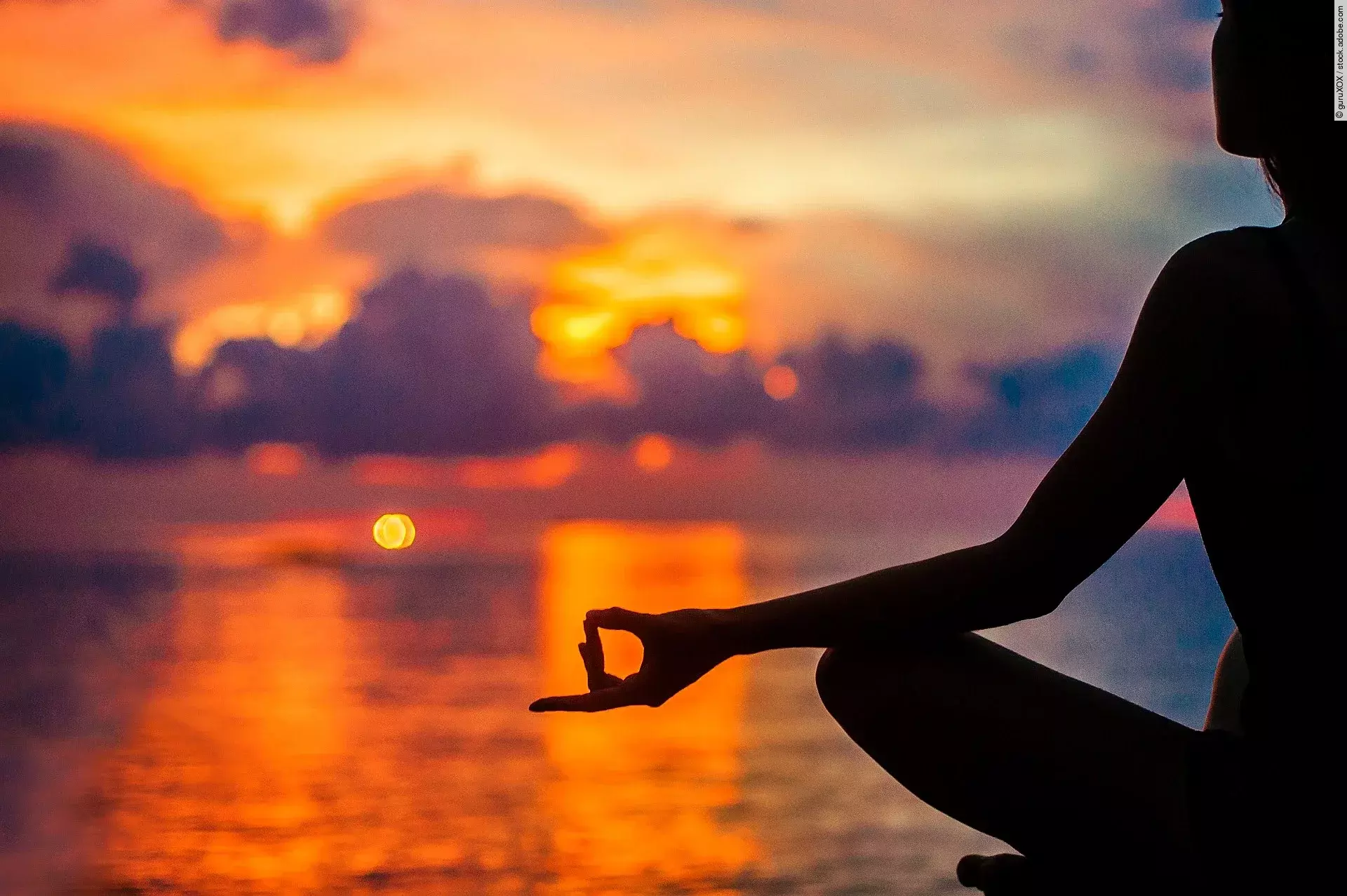 Eine Frau meditiert zur Entspannung am Meer im Sonnenuntergang. Eine Frau meditiert zur Entspannung am Meer im Sonnenuntergang.