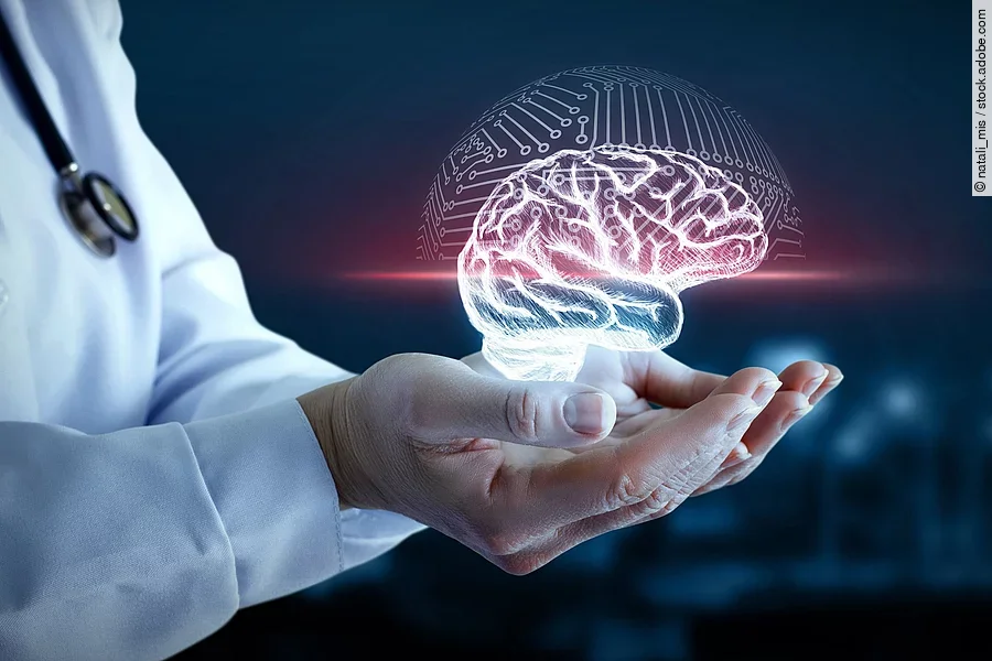 Hände von einer Person mit weißem Kittel halten ein virtuelles Gehirn fest