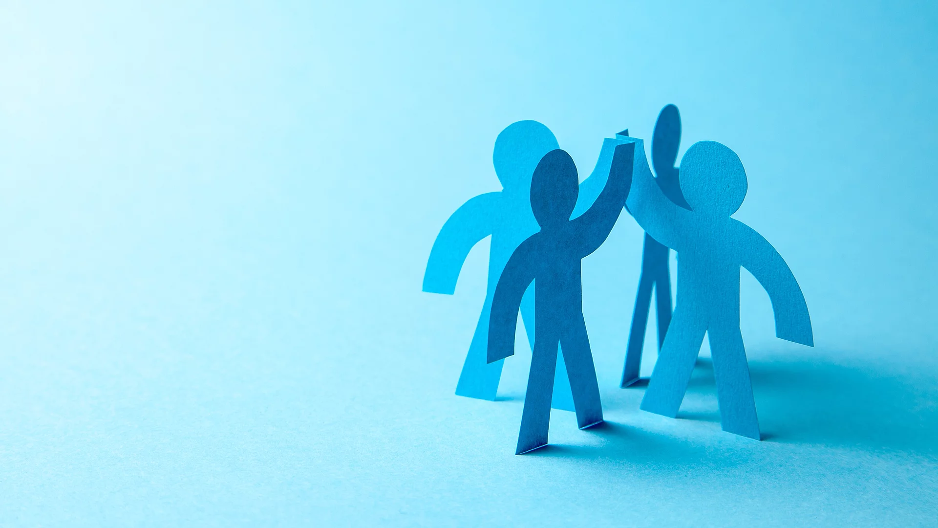 Eine Grafik zeigt blaue schemenhaft dargestellte Menschen, die im Kreis stehen und sich ein High Five geben.