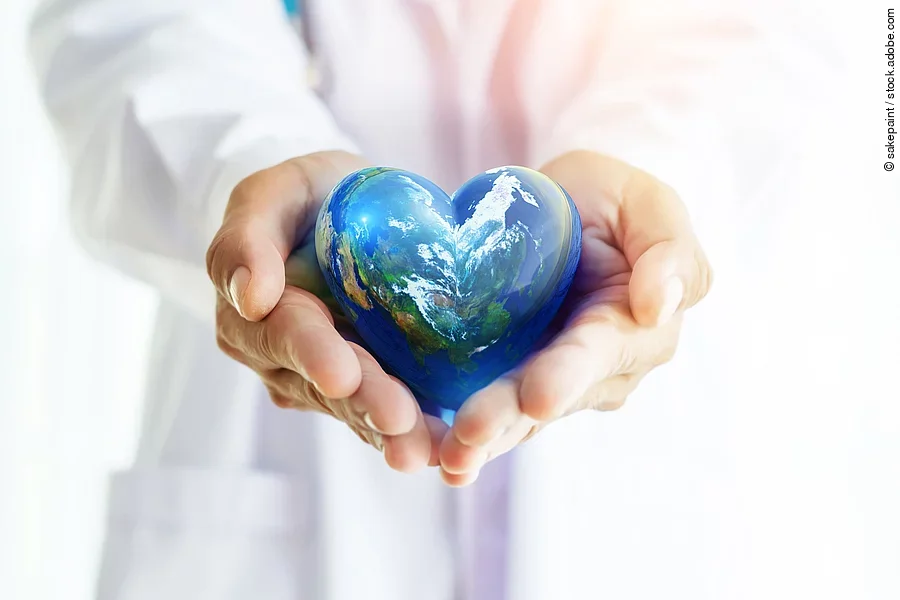Ein Arzt in weißem Kittel hält die herzförmige Erde in seinen Händen.