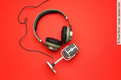 Kopfhörer und Mikrofon auf rotem Untergrund.