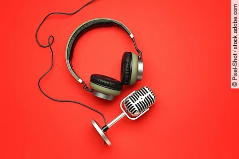 Kopfhörer und Mikrofon auf rotem Untergrund.