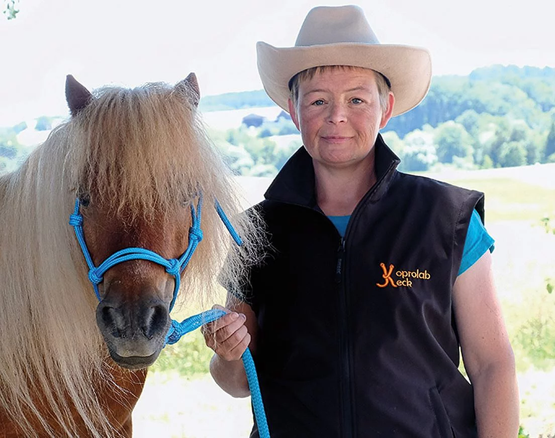 Nana Keck trägt einen beigen Cowboyhut und posiert mit einem braunen Pony für die Kamera.