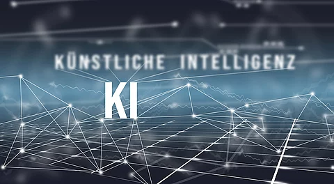 Auf blauem Hintergrund mit Vernetzungen steht "KÜNSTLICHE INTELLIGENZ" geschrieben.