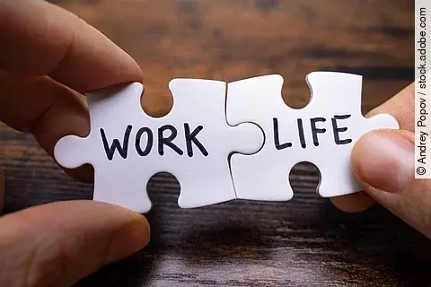 Zwei weiße Puzzleteile werden passend aneinander gehalten. Auf dem linken Teil steht in schwarzer Schrift "WORK" und auf dem anderen Puzzleteil steht "LIFE". 