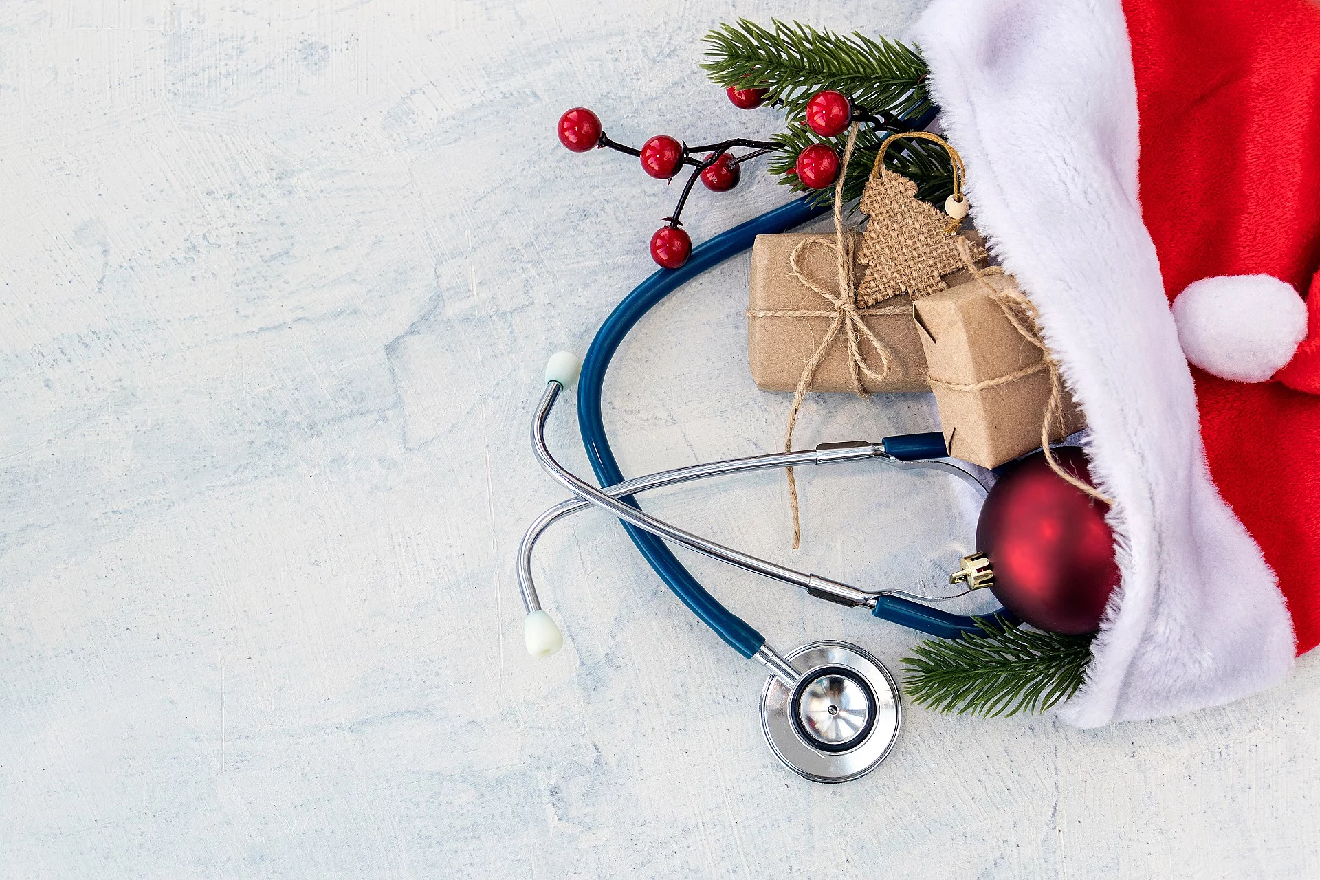 In einer Weihnachtsmütze sind kleine Geschenke, Tannenzweige und ein Stethoskop.