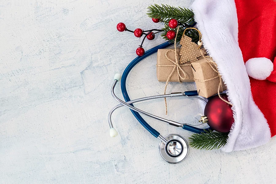 In einer Weihnachtsmütze sind kleine Geschenke, Tannenzweige und ein Stethoskop.