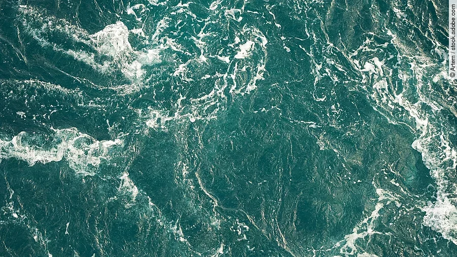 Blick von oben auf das Meer, welches Wellen schlägt.