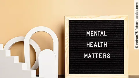 Ein Motivationszitat zum Thema psychische Gesundheit auf einer Buchstabenwand. Auf der Wand steht in weißer Schrift: MENTAL HEALTH MATTERS. Die Tafel steht auf einem schwarzen Tisch, vor einer gelben Wand.