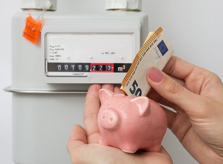 Energy saving concept. Woman's hand inserting Euro cash in piggy