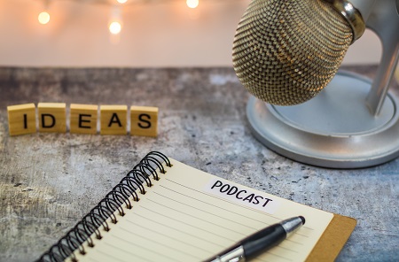 Podcast ideas concept with microphone, notepad, tablet on board