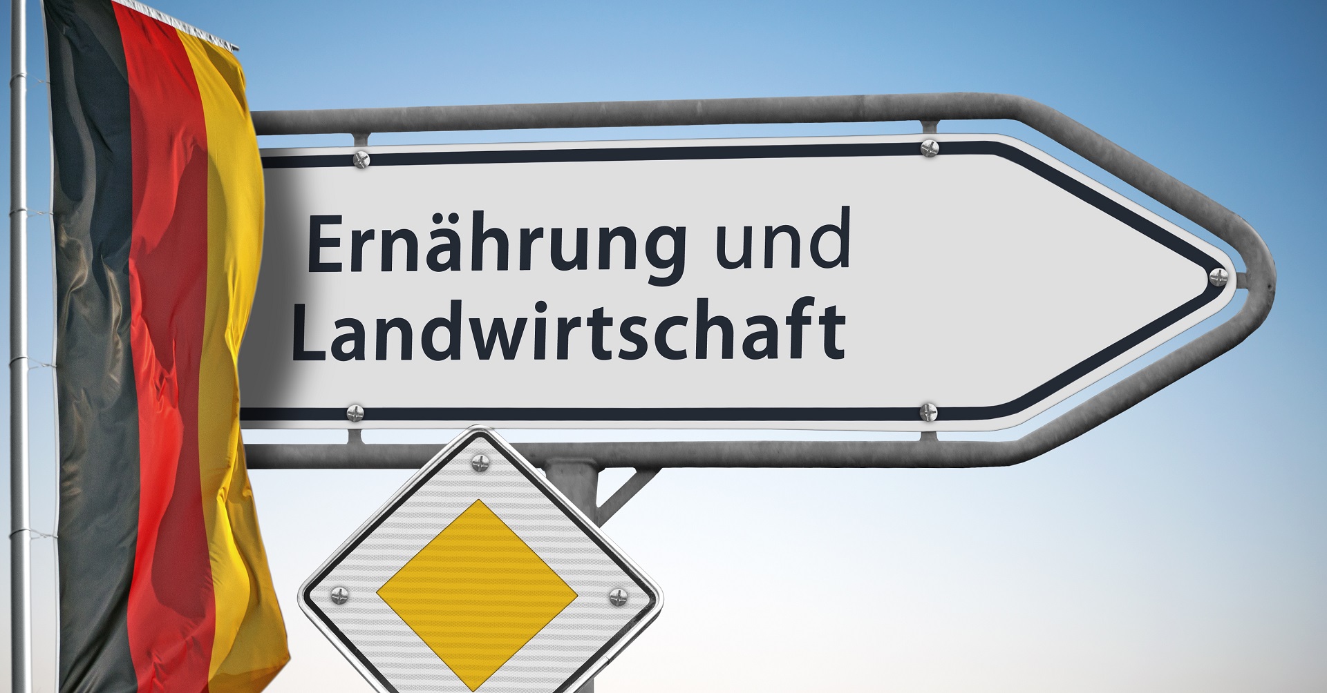 Ein weißes Straßenschild weist den Weg zum Bundesministerium für Ernährung und Landwirtschaft. Daneben hängt eine Deutschlandflagge.