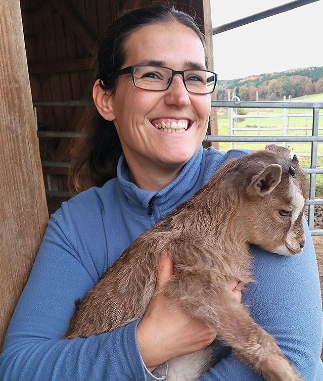 Anja Kaindl hält ein Ziegenbaby auf dem Arm.