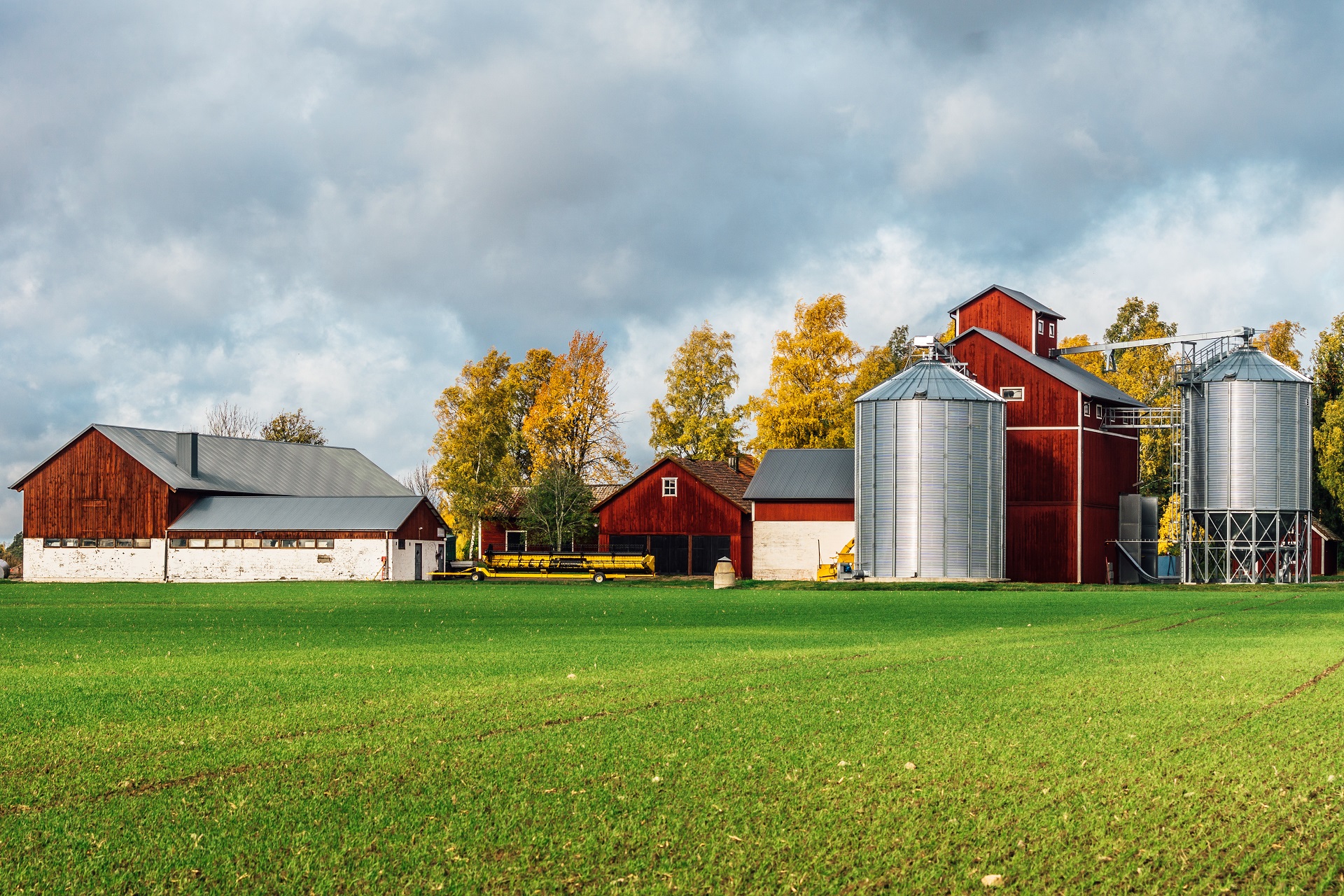 Ein Bauernhof in klassichem Schwedenrot hat eine große grünen Wiese und neu aussehende Silos.