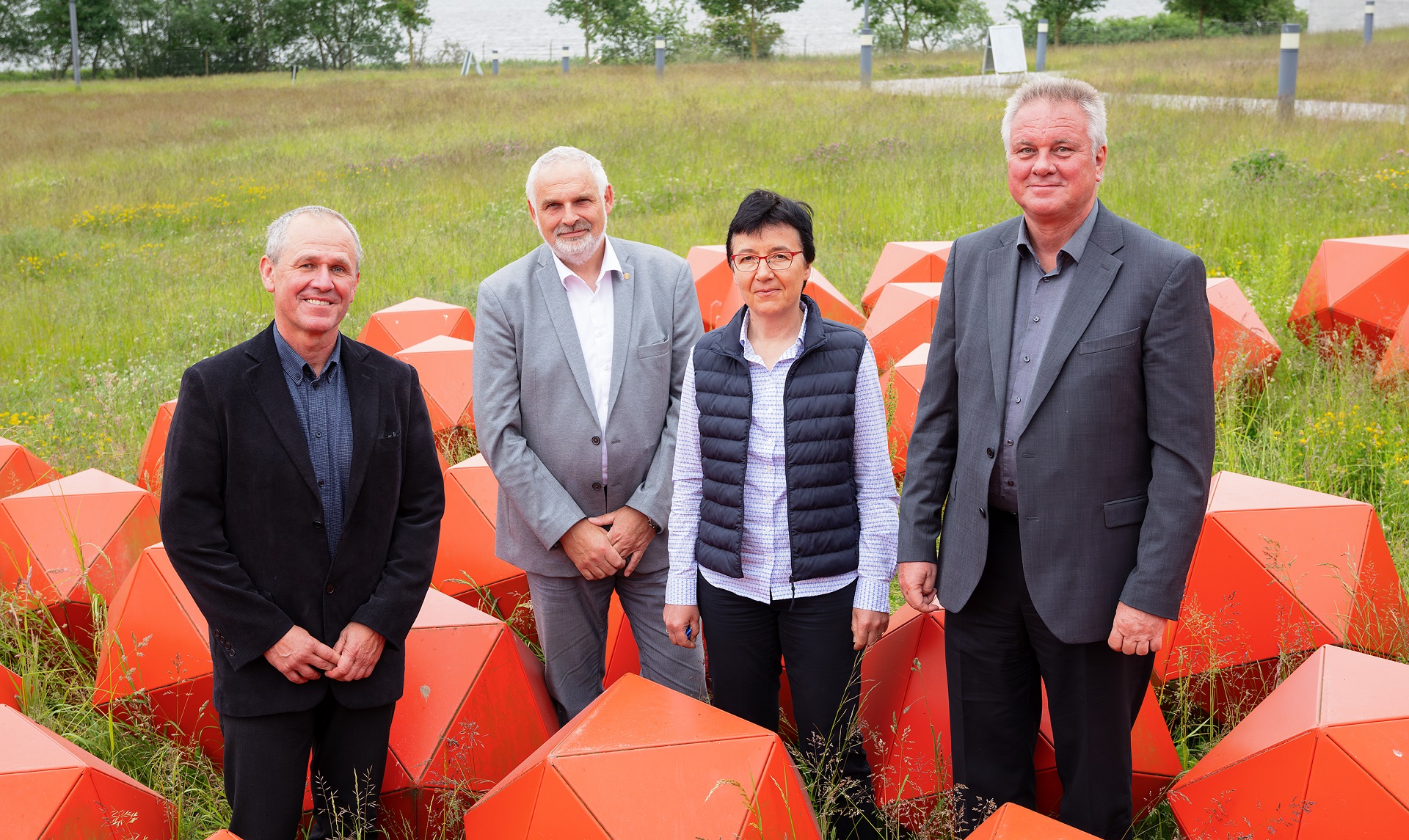 Der wiedergewählte Vorstand des FLI und die Präsidentin des Instituts posieren für die Kamera zwischen roten Skulpturen.