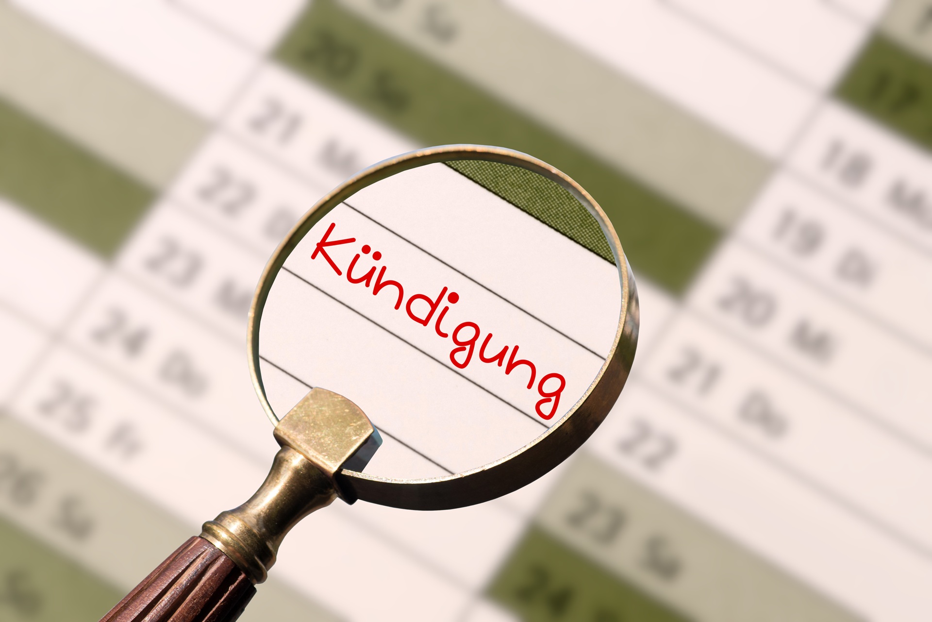 Eine Lupe wird über einen Jahreskalender gehalten. Durch die Lupe erkennt man einen Eintrag in den Kalender. In roter Schrift steht dort "Kündigung" geschrieben.