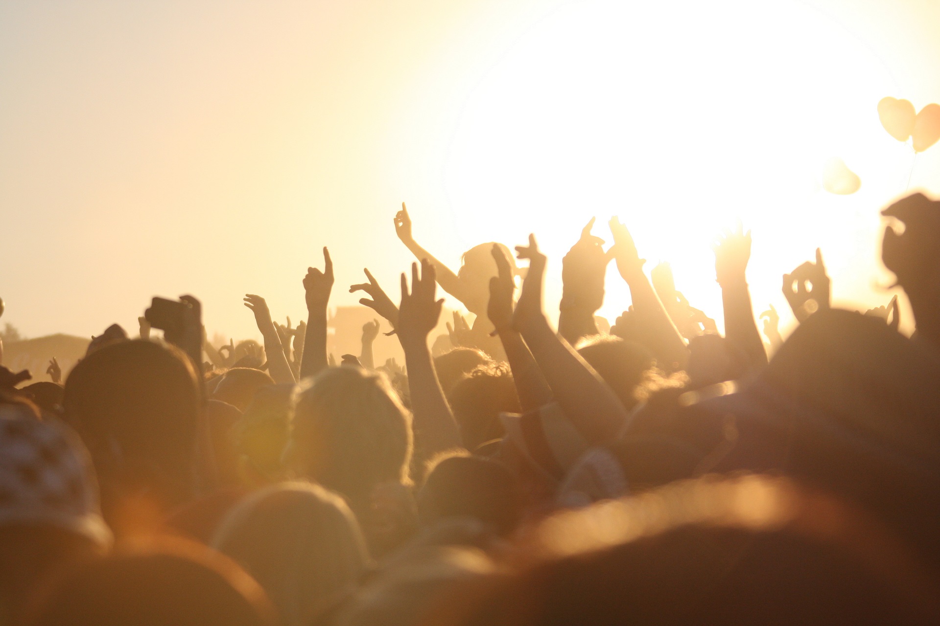 Viele Menschen tanzen, singen und feiern auf einem Festival im Sonnenlicht.