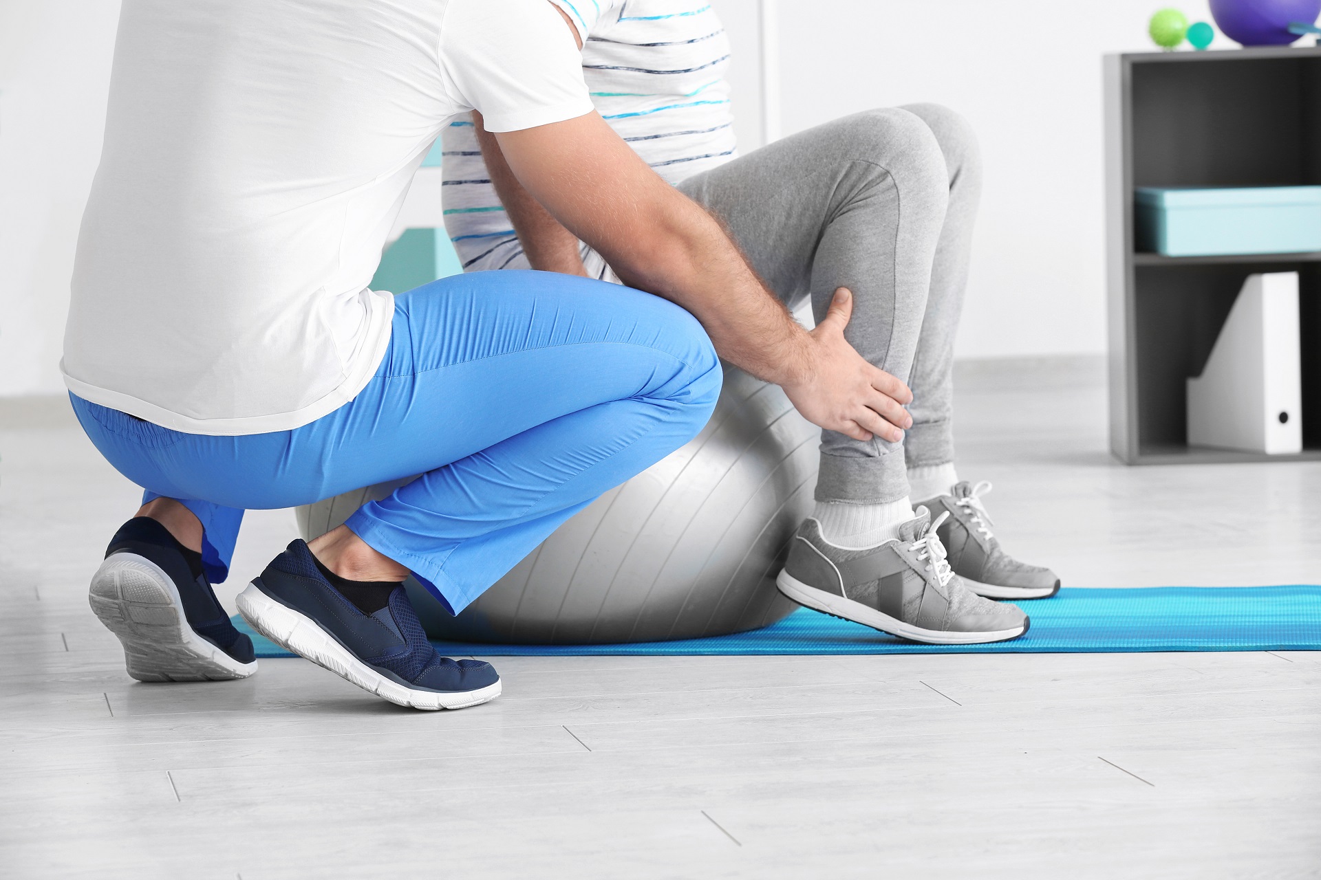 Ein Physiotherapeut arbeitet mit einer Person an einem Gymnastikball. 