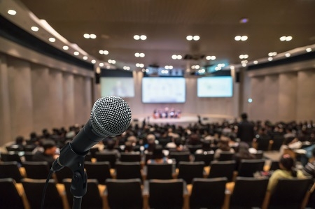 Microphone over the Abstract blurred photo of conference hall or